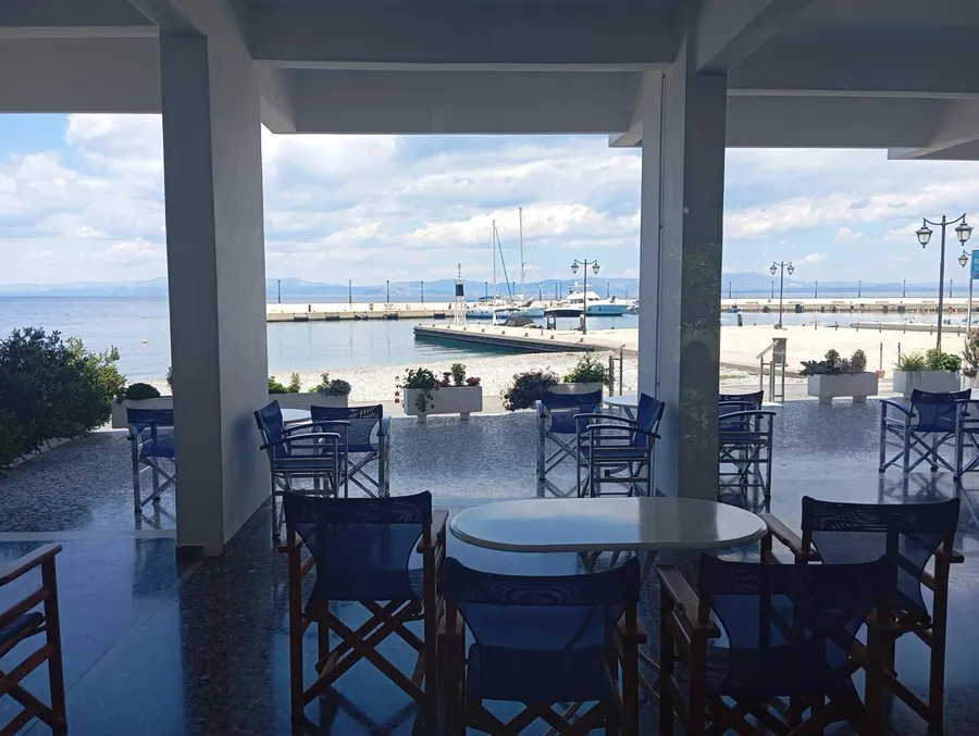 Η σκιερή βεράντα με τα μπλε τραπέζια μπροστά στη θάλασσα